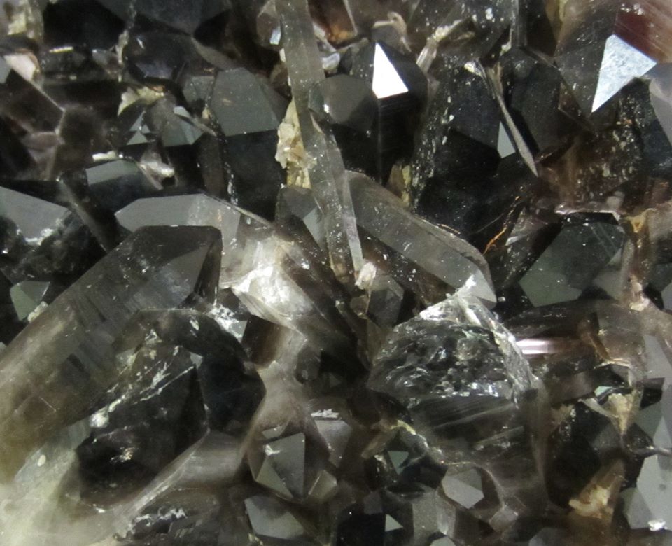 Close-up of dark, glossy crystal formations with sharp, angular edges and a reflective surface.