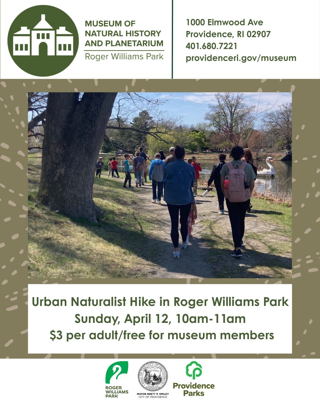 Group of people walking along a path in Roger Williams Park, surrounded by trees and water.